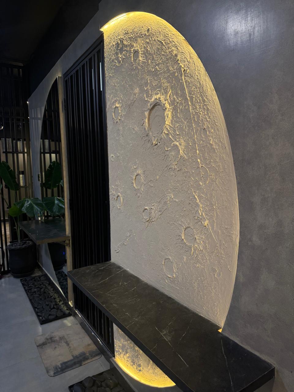 Close-up of the sculpted, backlit moon wall at The Man Redefined